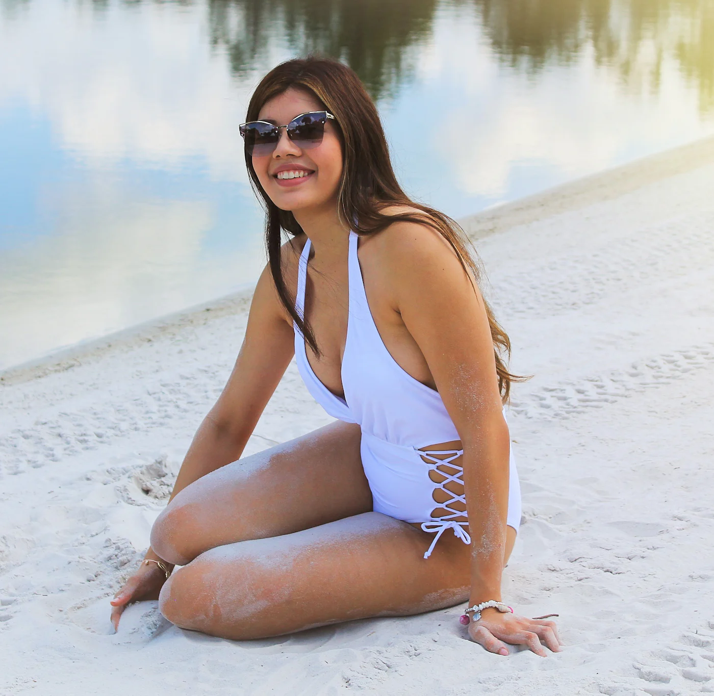 Donna sorridente in costume bianco sulla spiaggia